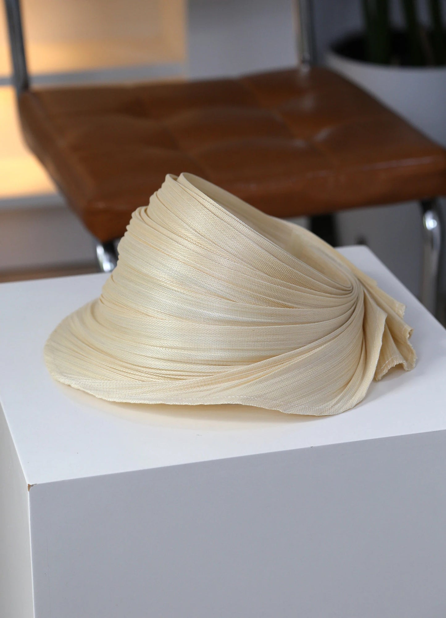 Natural Buntal straw open top sun hat with sculptural pleated brim for summer resort wear.