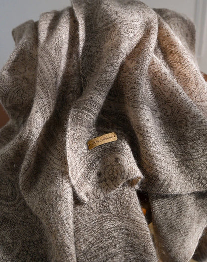 Close-up of plum brown cashmere scarf folds, highlighting the tonal paisley pattern and textured surface.