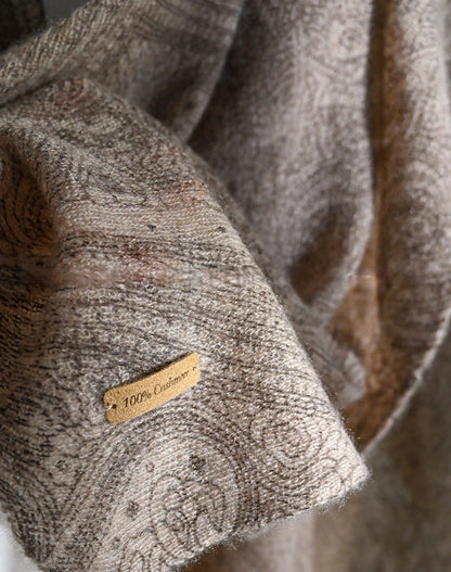 Plum brown cashmere scarf detail showing intricate paisley motifs and a 100% cashmere label.