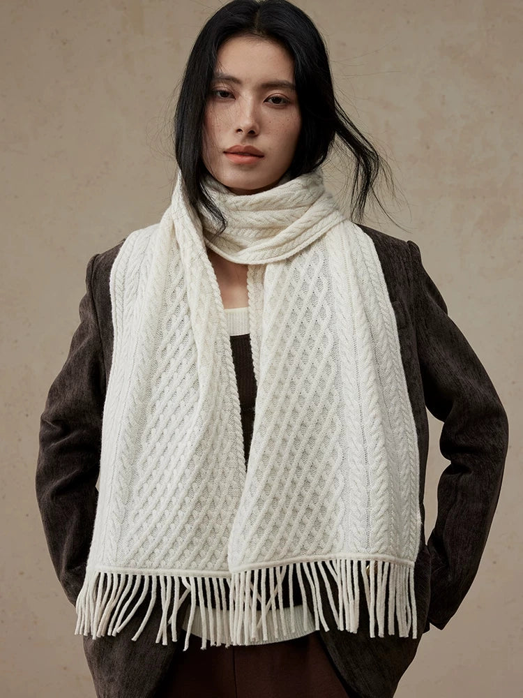 Pure white cable knit scarf wrapped around a model's neck, with fringed ends over a brown blazer.