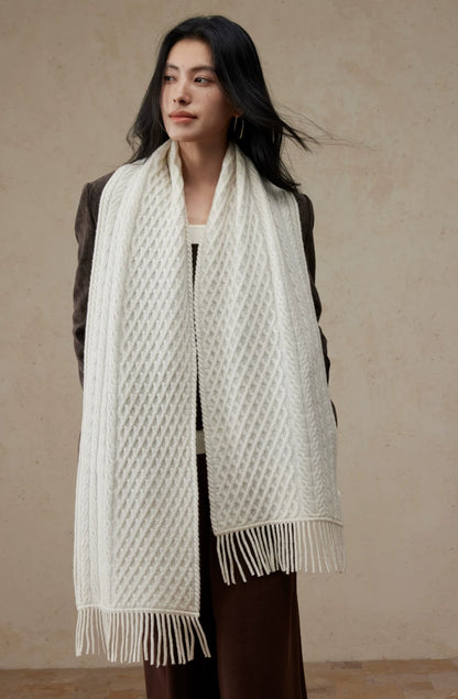 Pure white cable knit scarf draped around a model's neck, with long fringed ends hanging down the front.