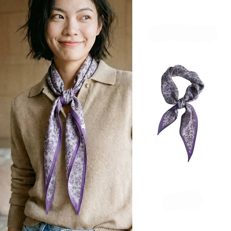 Woman wearing a purple paisley silk wool diamond scarf with a beige knit top
