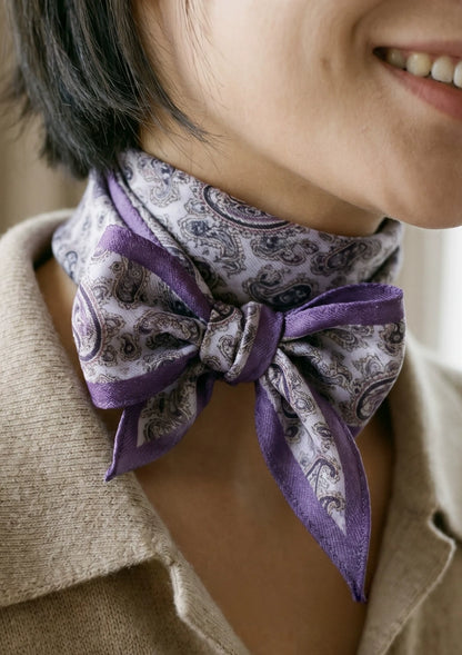 Close-up of a purple paisley diamond scarf tied in an elegant neck bow
