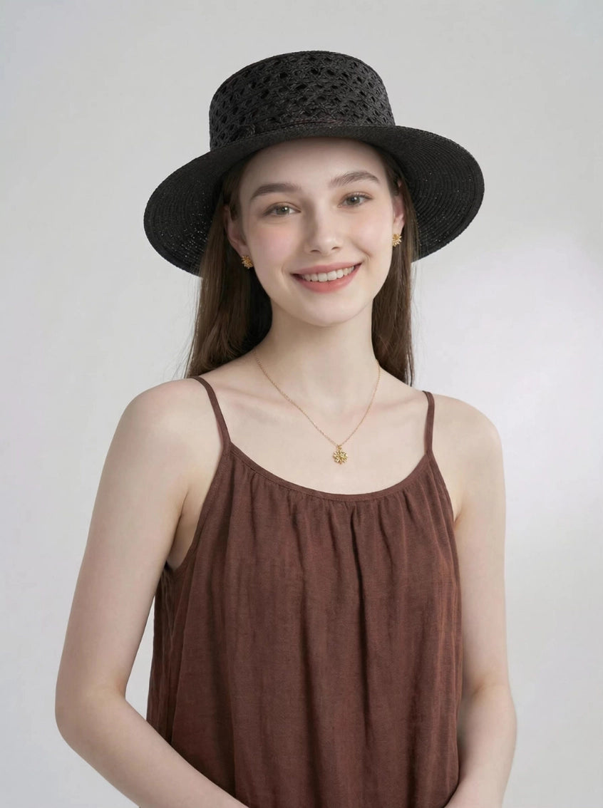 Model wearing black raffia straw boater hat with wide brim and crochet open weave.