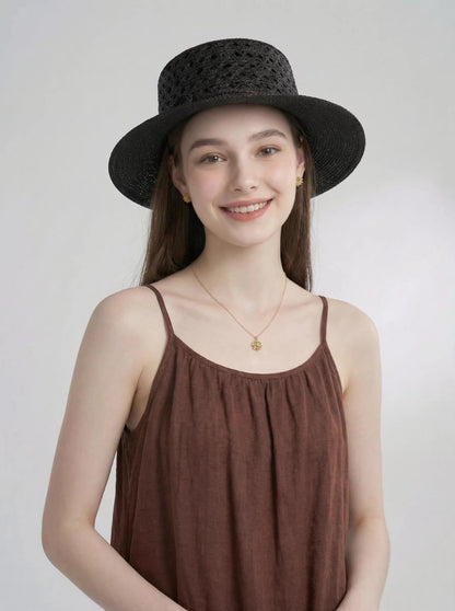Model wearing black raffia straw boater hat with wide brim and crochet open weave.