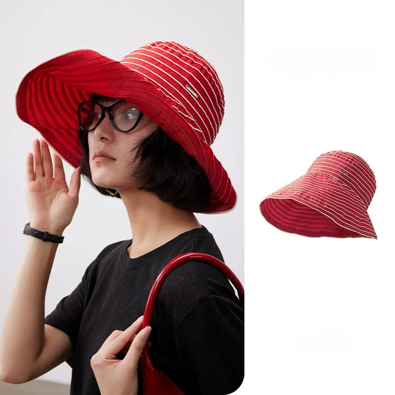Woman wearing a red and white striped foldable wide brim sun hat with a stylish summer outfit.