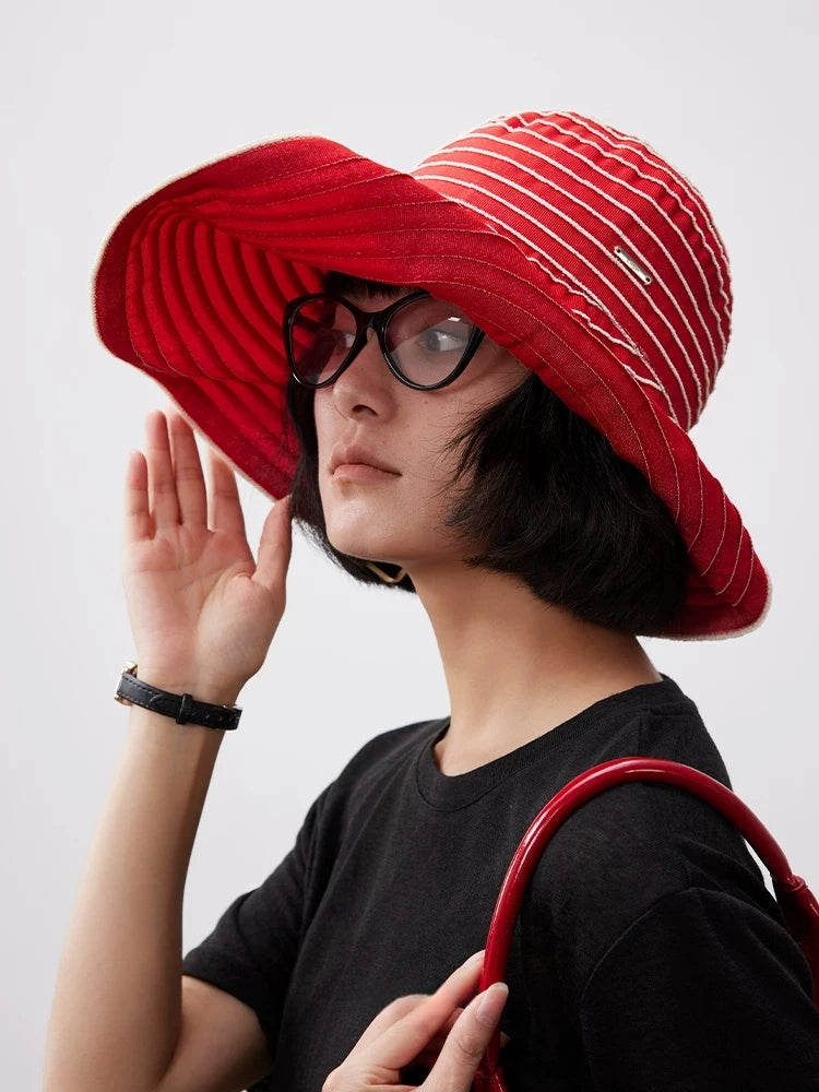 Woman styling a packable red striped sun hat for casual outdoor summer wear.
