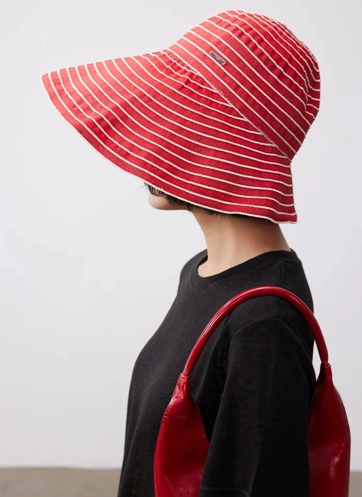 Side view of a red and white foldable summer hat with a sculpted wide brim.