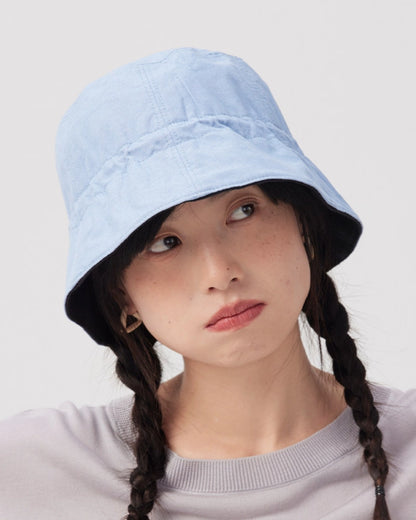 Woman wearing the light blue side of a reversible cotton linen bucket hat with a black navy lining