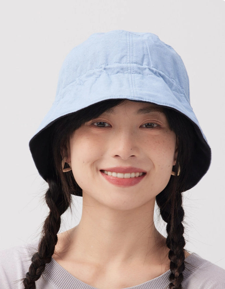 Front view of a light blue reversible cotton linen bucket hat styled for casual summer wear