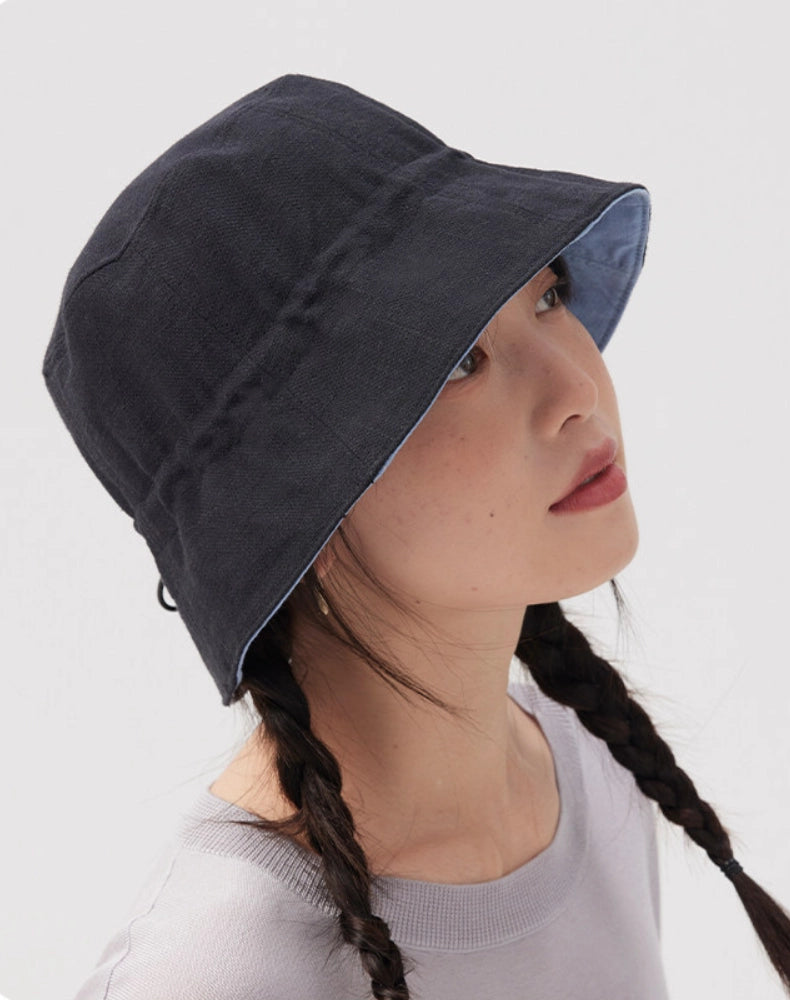 Side view of a woman wearing a black navy cotton linen bucket hat with a softly structured brim