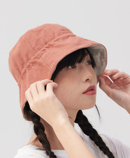 Side view of an orange pink reversible bucket hat made from a breathable cotton linen blend