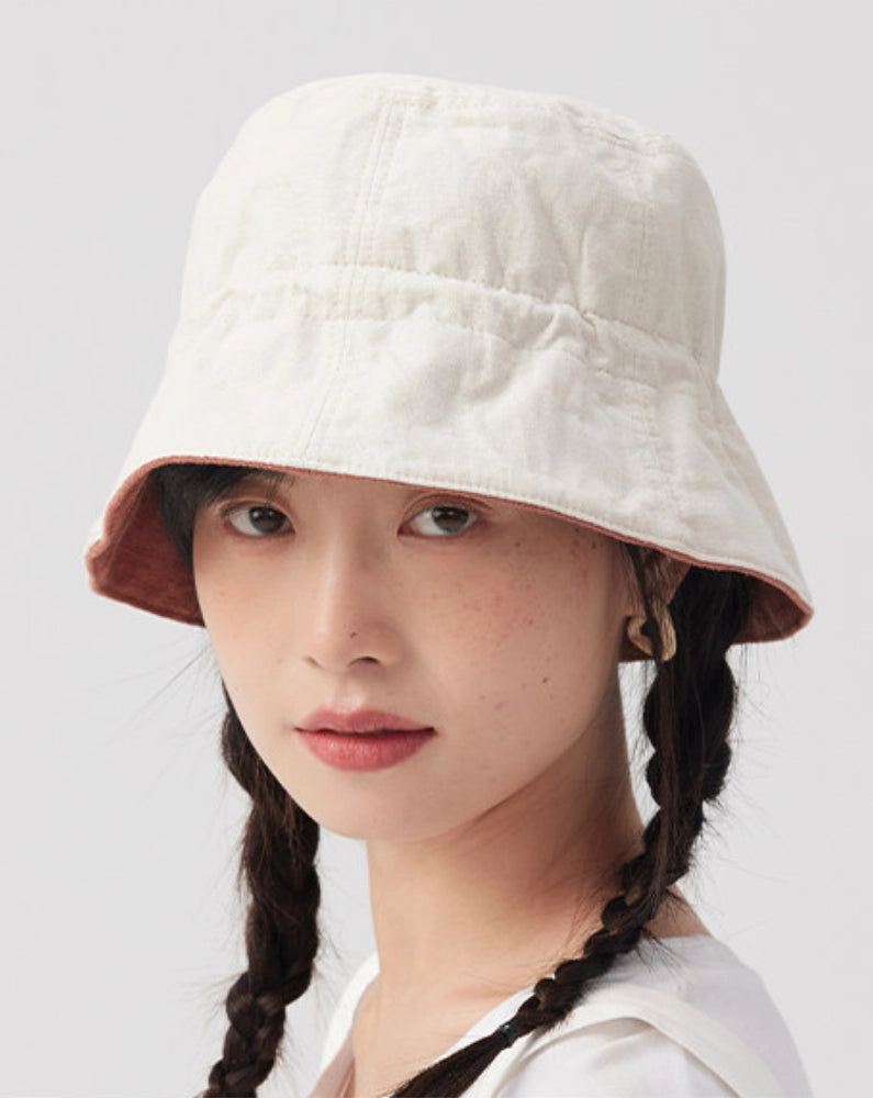 Close-up of a light neutral reversible cotton linen bucket hat styled for everyday summer wear