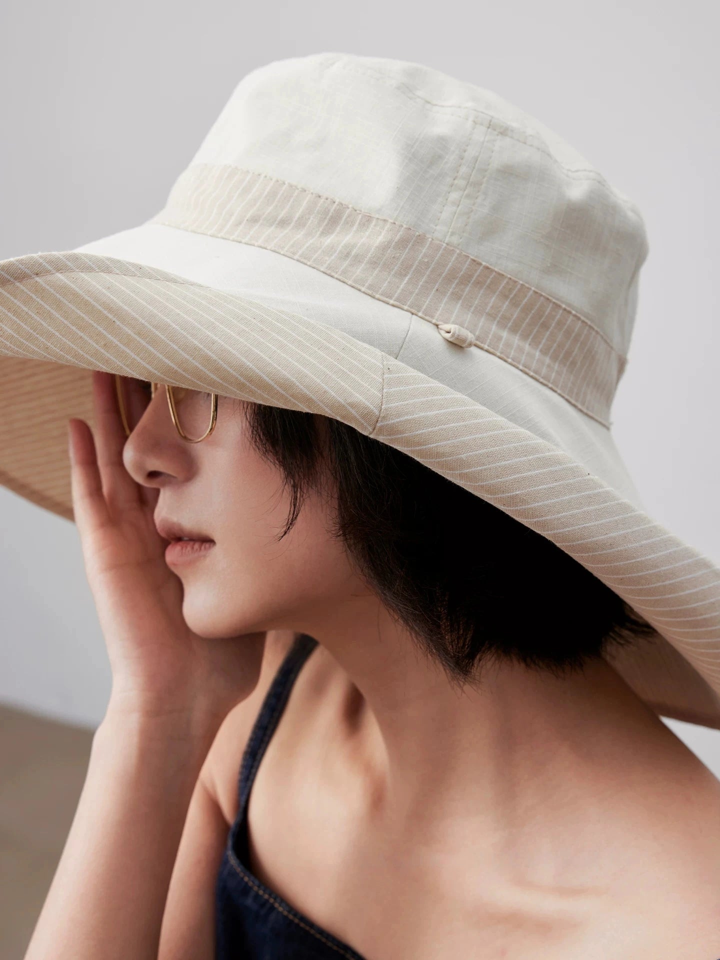 Close-up of ivory reversible cotton linen sun hat with wide brim and breathable texture