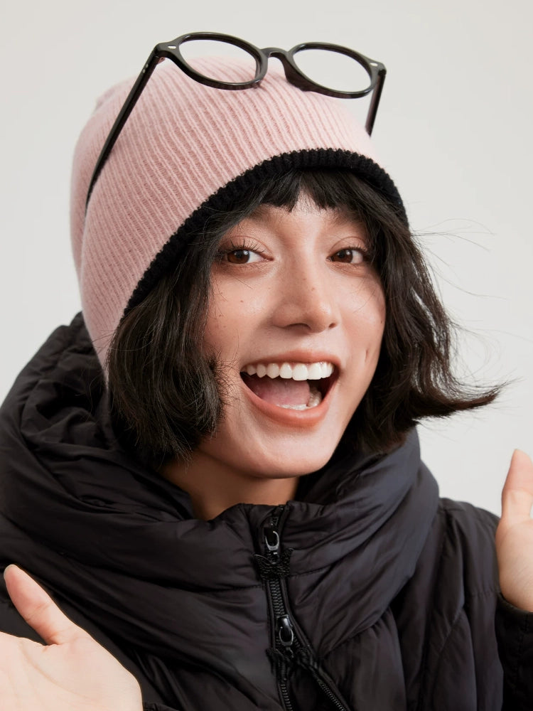Cherry blossom pink reversible wool beanie with a black edge, modeled with glasses resting on top.