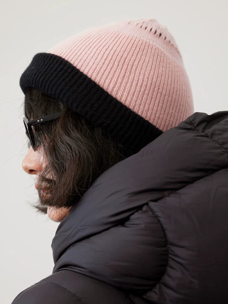 Side view of a cherry blossom pink rib-knit wool beanie with a wide black fold-over cuff.