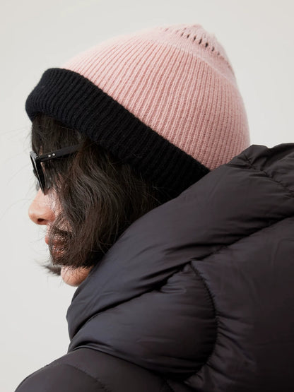 Side view of a cherry blossom pink rib-knit wool beanie with a wide black fold-over cuff.