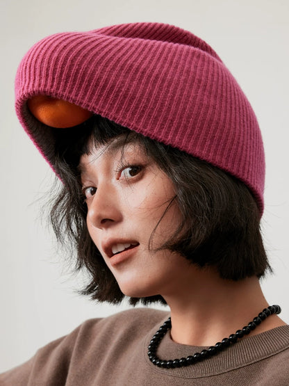 Rose pink wool beanie with a loosely folded front edge, highlighting its ribbed knit texture.