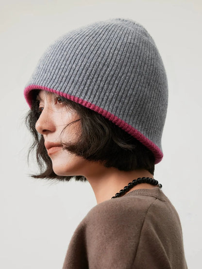 Side view of a light gray reversible wool beanie with a narrow rose pink edge.