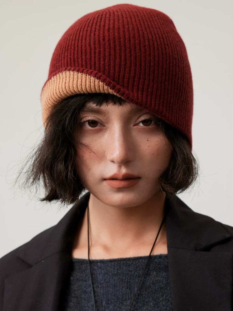 Front view of a rust brown reversible wool beanie with a partially turned-up camel edge.