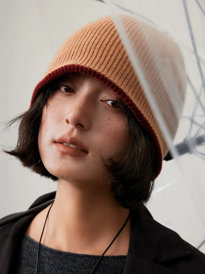 Close-up of a camel reversible wool beanie with a narrow rust brown edge, worn low on the forehead.