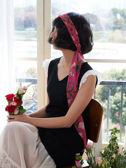 Model holding flowers while wearing a rose red morning glory skinny silk scarf
