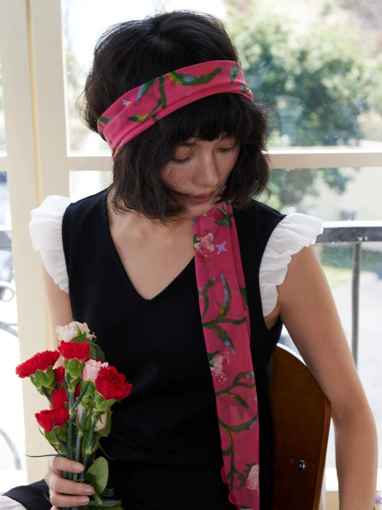 Model wearing a rose red morning glory skinny silk scarf with black dress and summer hat