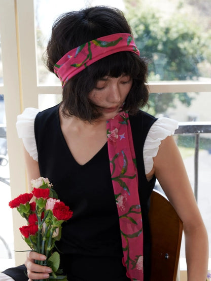 Model wearing a rose red morning glory skinny silk scarf with black dress and summer hat