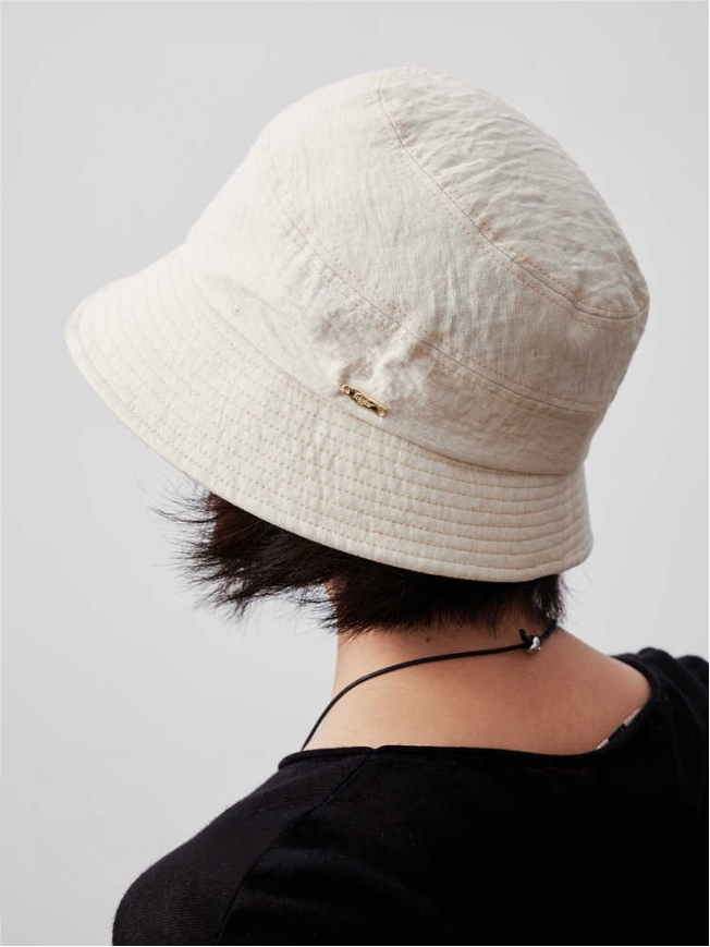 Off white short brim bucket hat side view on model, foldable cotton linen women's sun hat