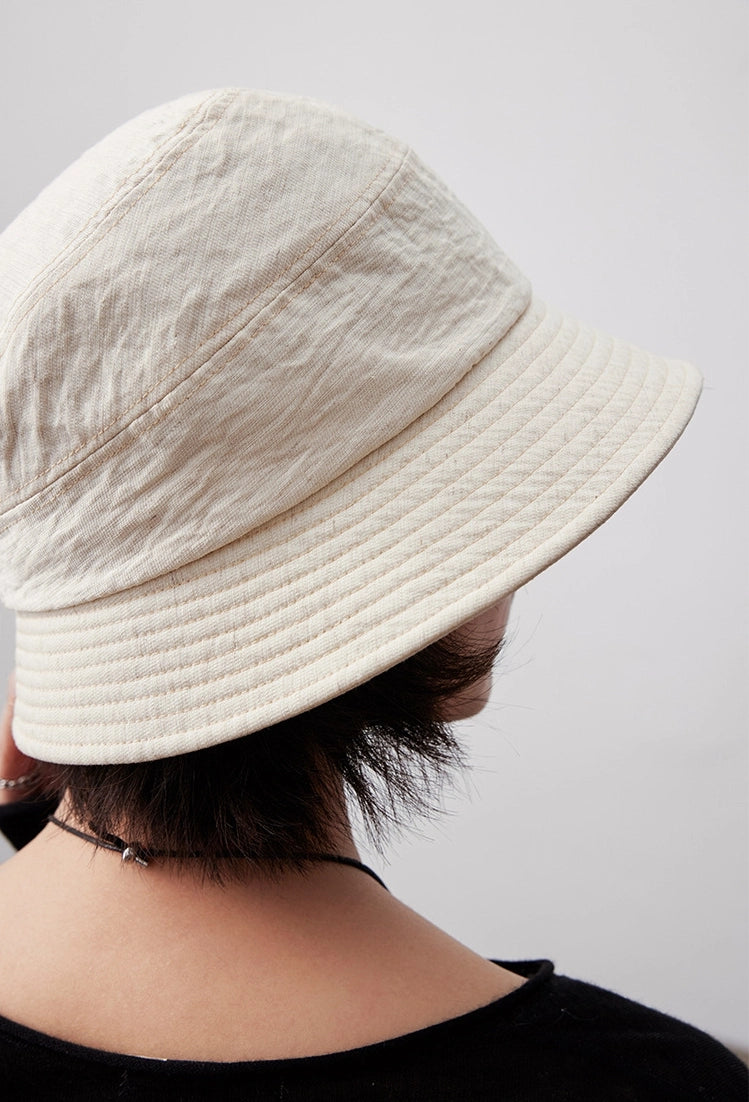 Off white short brim bucket hat close-up on model, minimalist foldable cotton linen hat