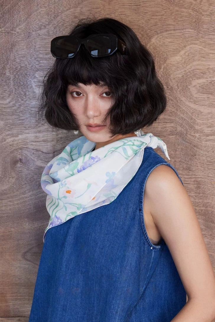 Watercolor floral silk scarf styled as a soft neck scarf over a blue sleeveless dress