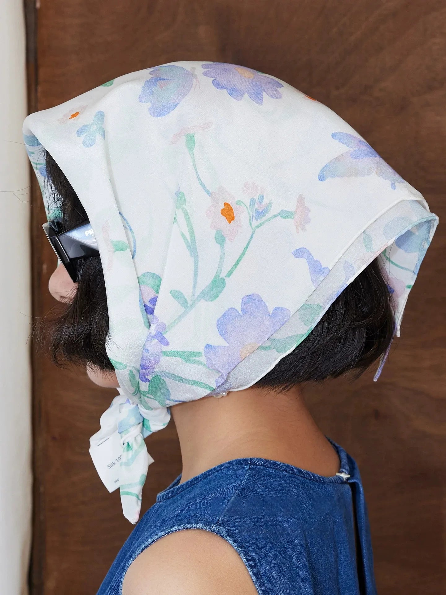 Close-up of elegant watercolor floral silk headscarf tied at the side with pastel botanical details