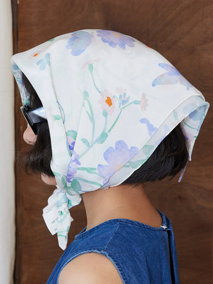 Close-up of elegant watercolor floral silk headscarf tied at the side with pastel botanical details