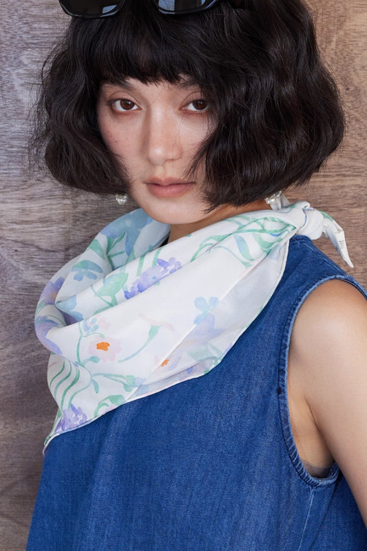 Square silk scarf with watercolor floral print, styled as a chic neck accessory.