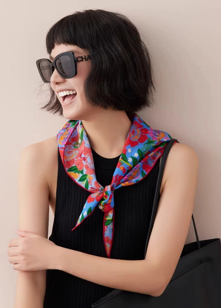 woman styling silk triangle scarf as chic neck accessory with sunglasses