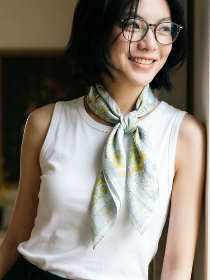 Woman wearing a Snow Mountain Blue elephant floral silk scarf loosely tied at the neck