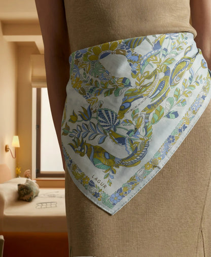 Snow Mountain Blue elephant floral silk square scarf styled as a waist accent over neutral trousers