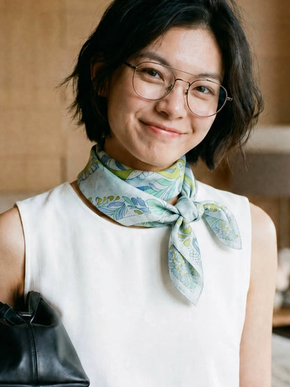 Woman wearing a Snow Mountain Blue botanical elephant silk scarf with a soft front knot