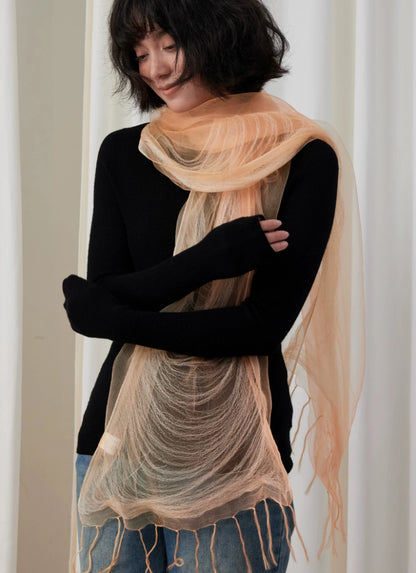 Woman styling a lightweight sweet orange silk wrap over a black outfit