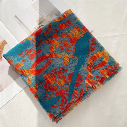 Folded teal peacock print wool scarf with a vivid red flame pattern on a light fabric surface