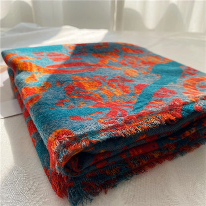 Close-up of folded 100% wool scarf showing the teal and red print, soft texture and fine fringe