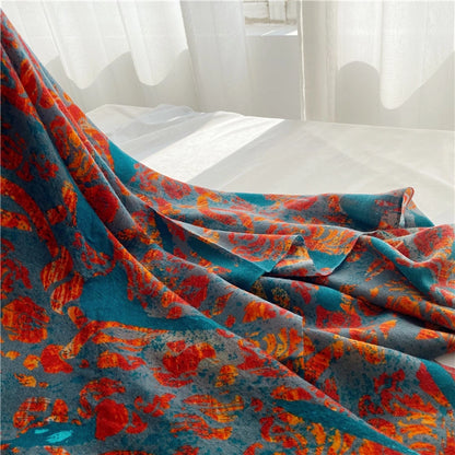 Oversized peacock print wool wrap draped in flowing folds across a white bed