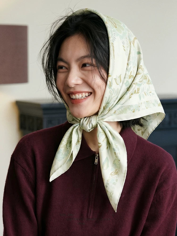 Woman wearing a tender green elephant floral silk scarf as a headscarf tied under the chin