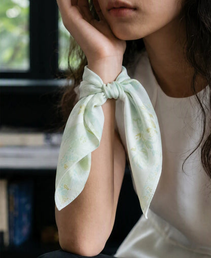 Tender green elephant floral silk scarf tied around the wrist with softly draped ends