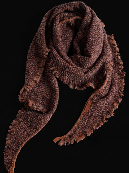 Terracotta cashmere triangle scarf loosely looped, with textured knit and fringed ends against a black background.