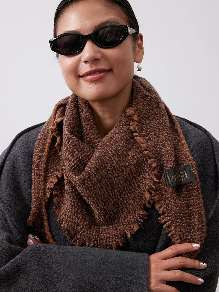 Model wearing a terracotta cashmere triangle scarf with the point draped over a charcoal sweater.