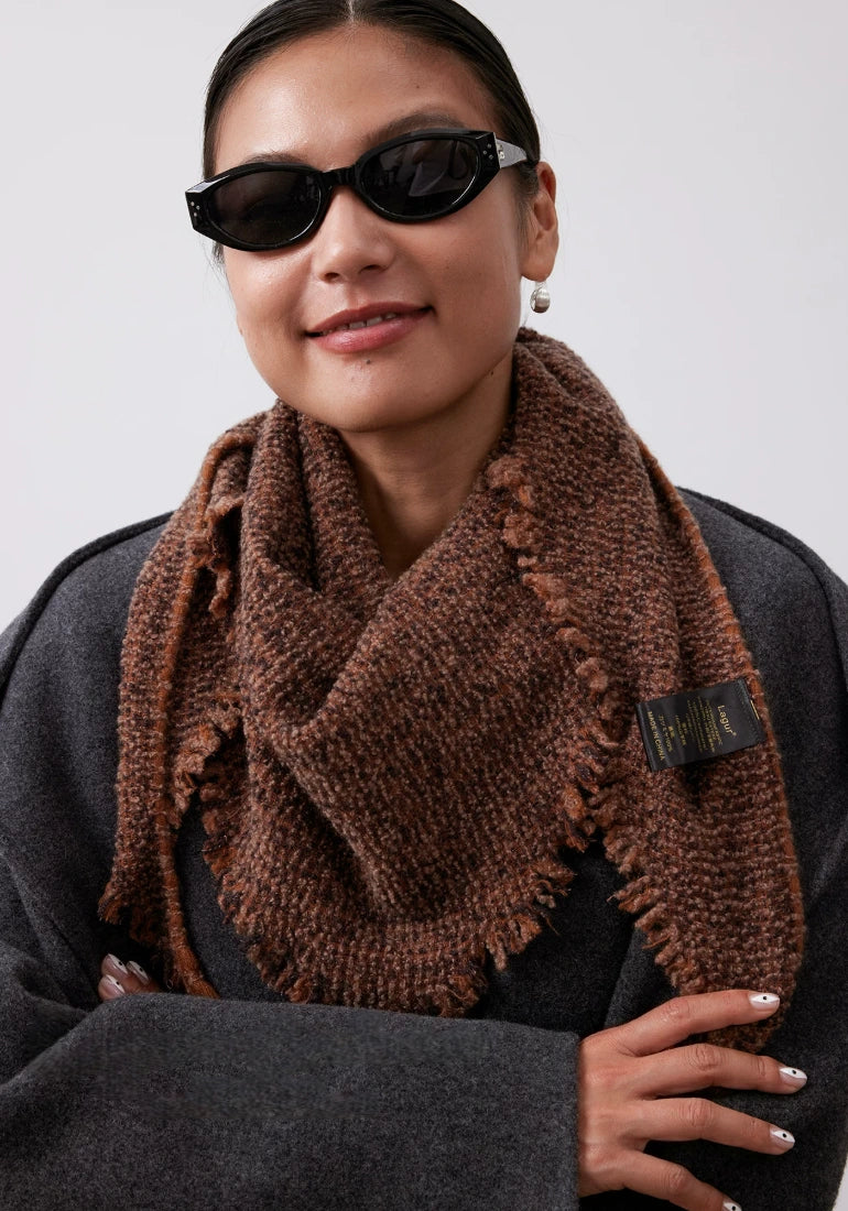 Terracotta cashmere triangle scarf worn over a charcoal sweater, with short fringe framing the front point.