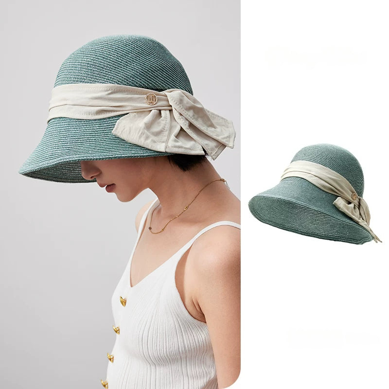 Turquoise green wide brim straw sun hat with white bow ribbon detail, shown in a soft summer styling view.