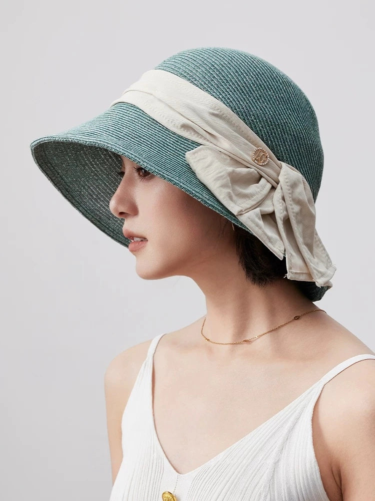 Turquoise green paper straw sun hat with wide brim and ribbon detail, styled with a white summer outfit.
