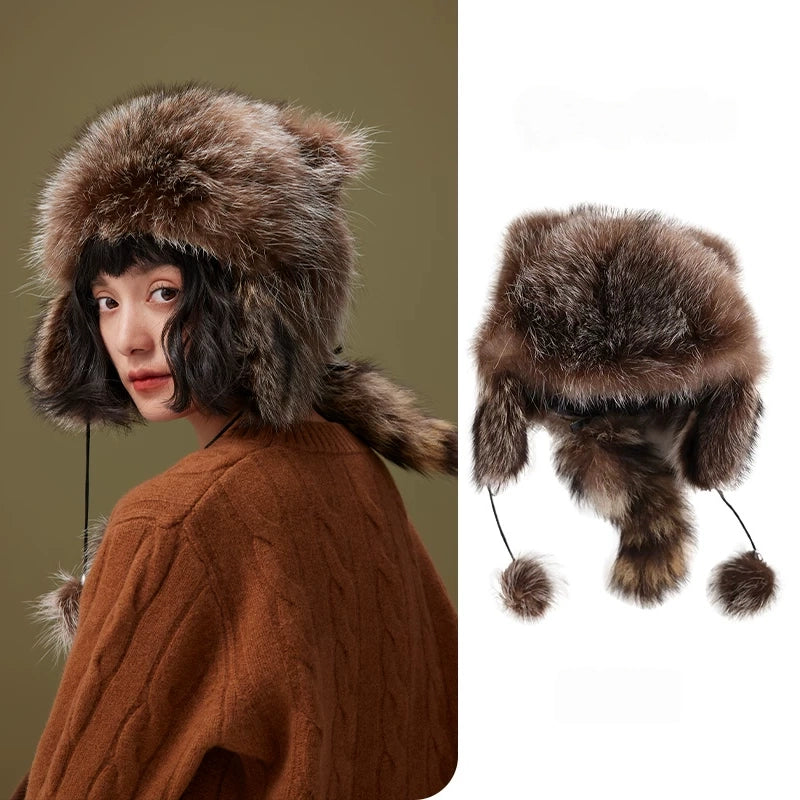 Model and product views of a brown-grey fur trapper hat with ear flaps, pom-pom cords and a raccoon-style tail.